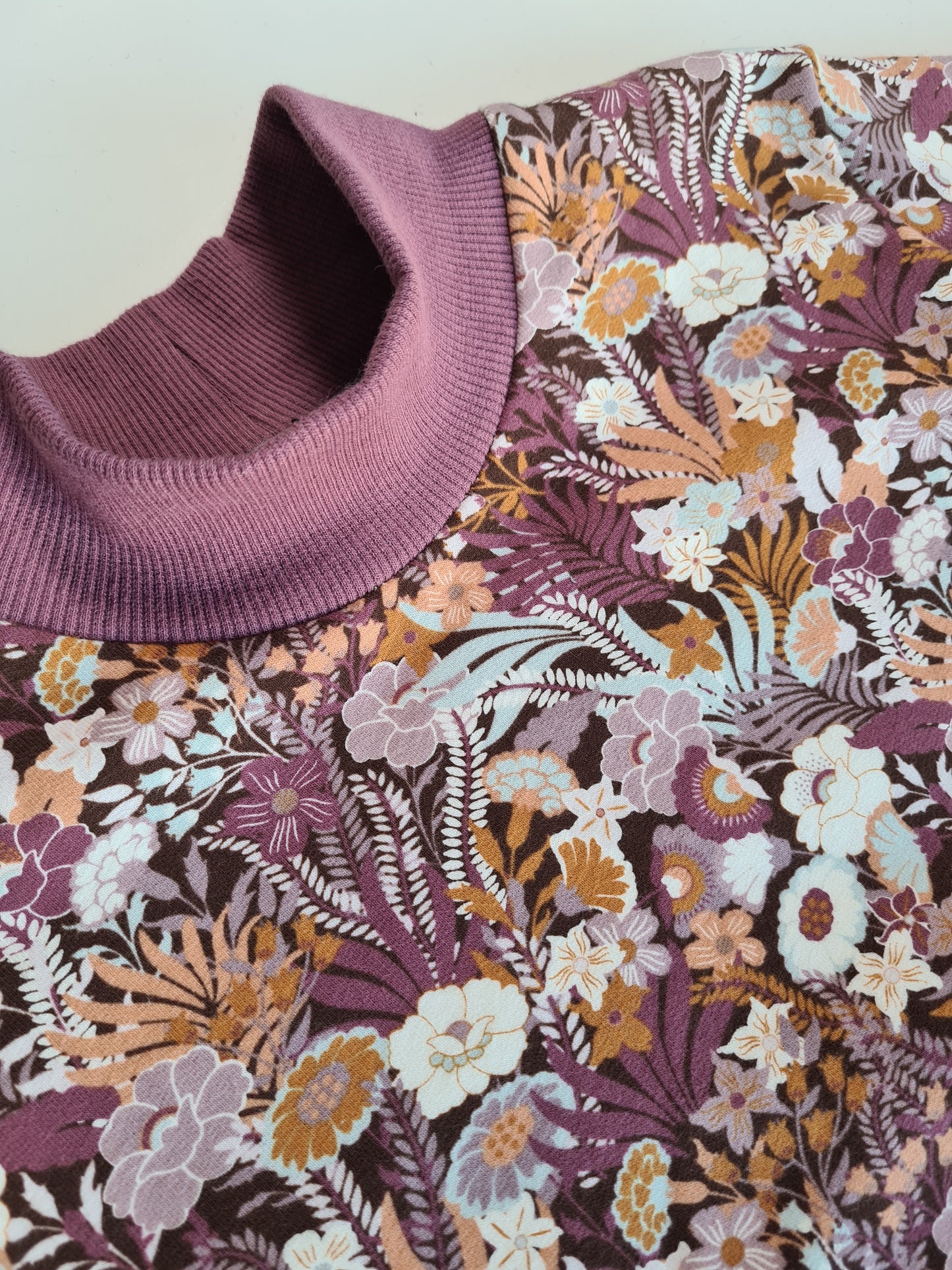 Nahaufnahme des floralen Longsleeves mit lila Bündchen. Stilvolles Design mit nachhaltigen Materialien für bequeme und modische Kindermode.