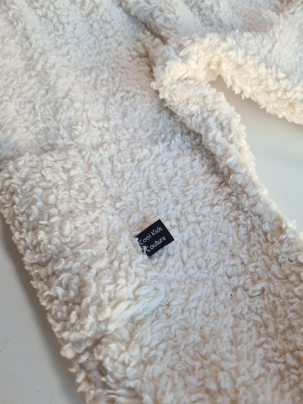 Detailaufnahme des Labels 'Cool Kids Couture' auf dem Bio-Baumwoll-Teddy Set. Hochwertige, nachhaltige Kinderkleidung mit stilvollem Design.