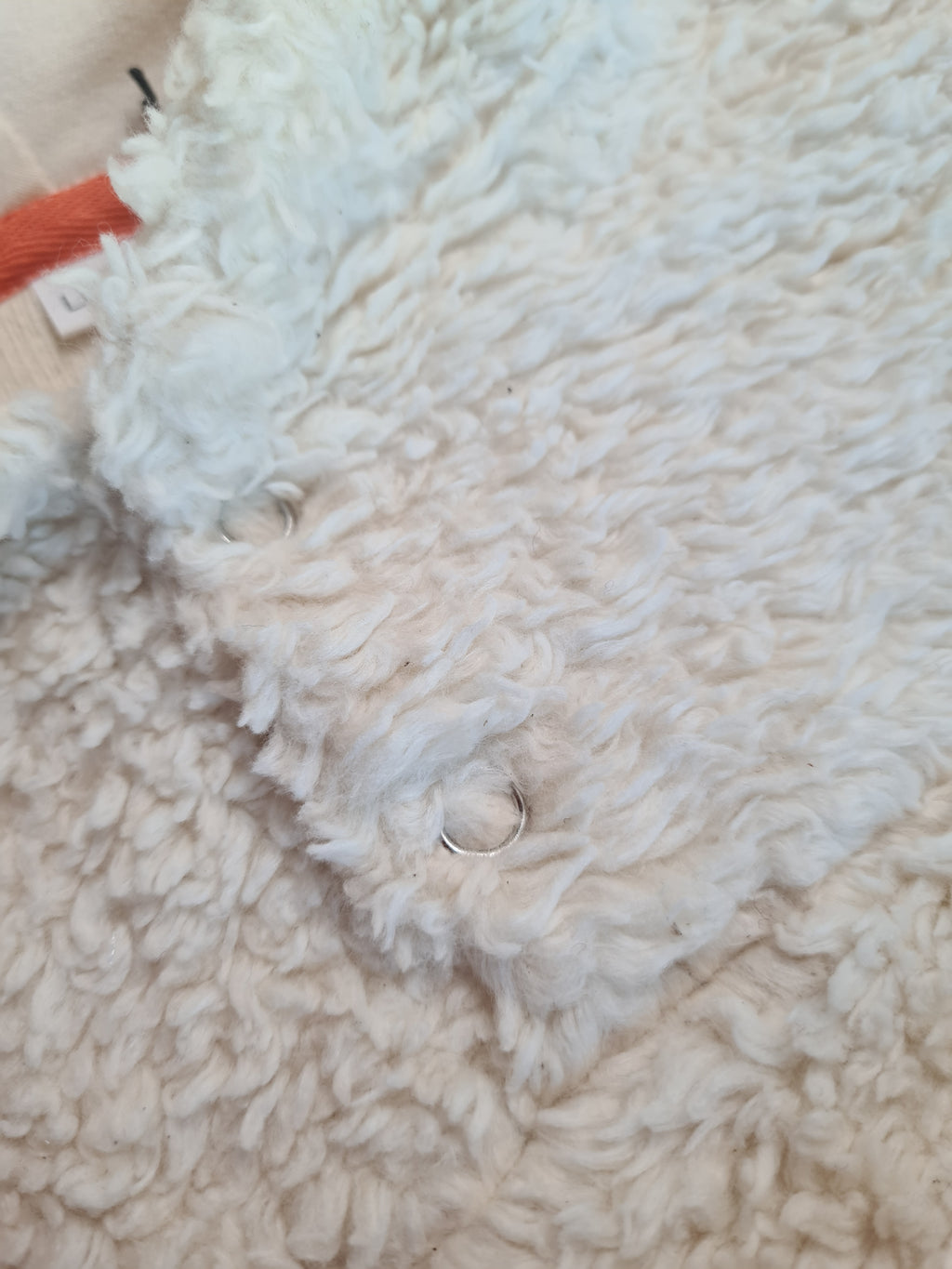 Nahaufnahme des kuscheligen Bio-Baumwoll-Teddy Stoffs mit Druckknöpfen. Hochwertige, nachhaltige Babybekleidung für Wärme und Komfort.