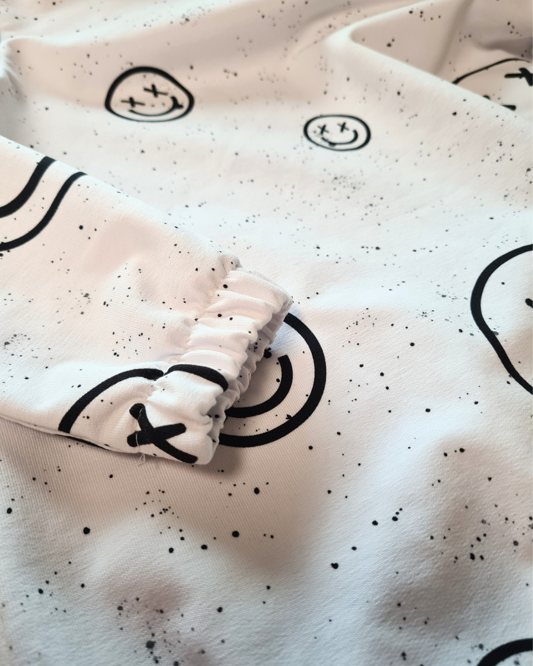 Nahaufnahme des weißen Hoodies mit Smiley-Print aus dem coolen Set für Jungs Gr. 116/122. Elastischer Ärmelbund für optimalen Tragekomfort.