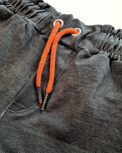 Nahaufnahme der schwarzen Jeans mit Gummibund und orangefarbener Kordel aus dem coolen Set für Jungs Gr. 116/122. Bequemer und moderner Look.